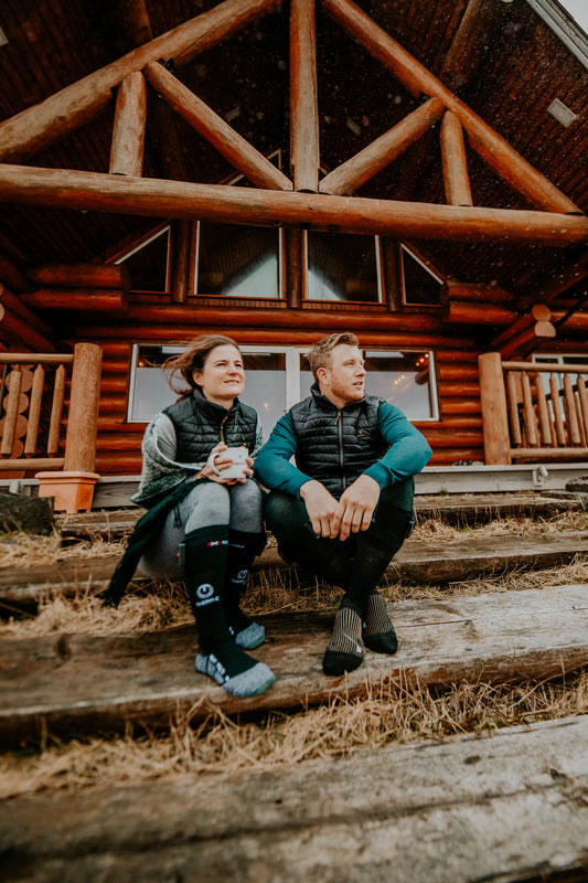 Couple sat on ski chalet steps wearing heated socks